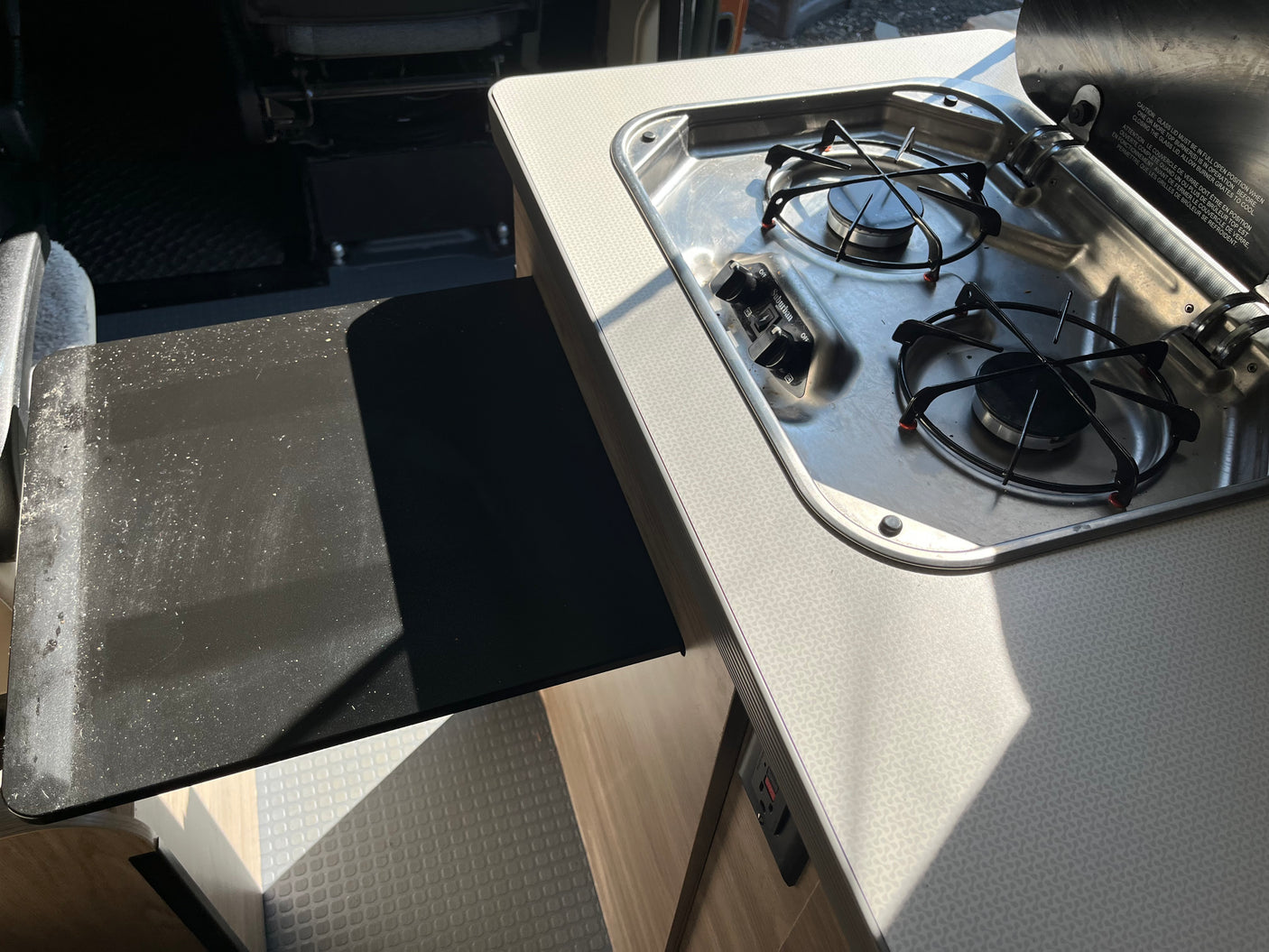 RV rental kitchen: a clean two-burner Suburban stovetop with an open lid, plus a pull-out counter extension.