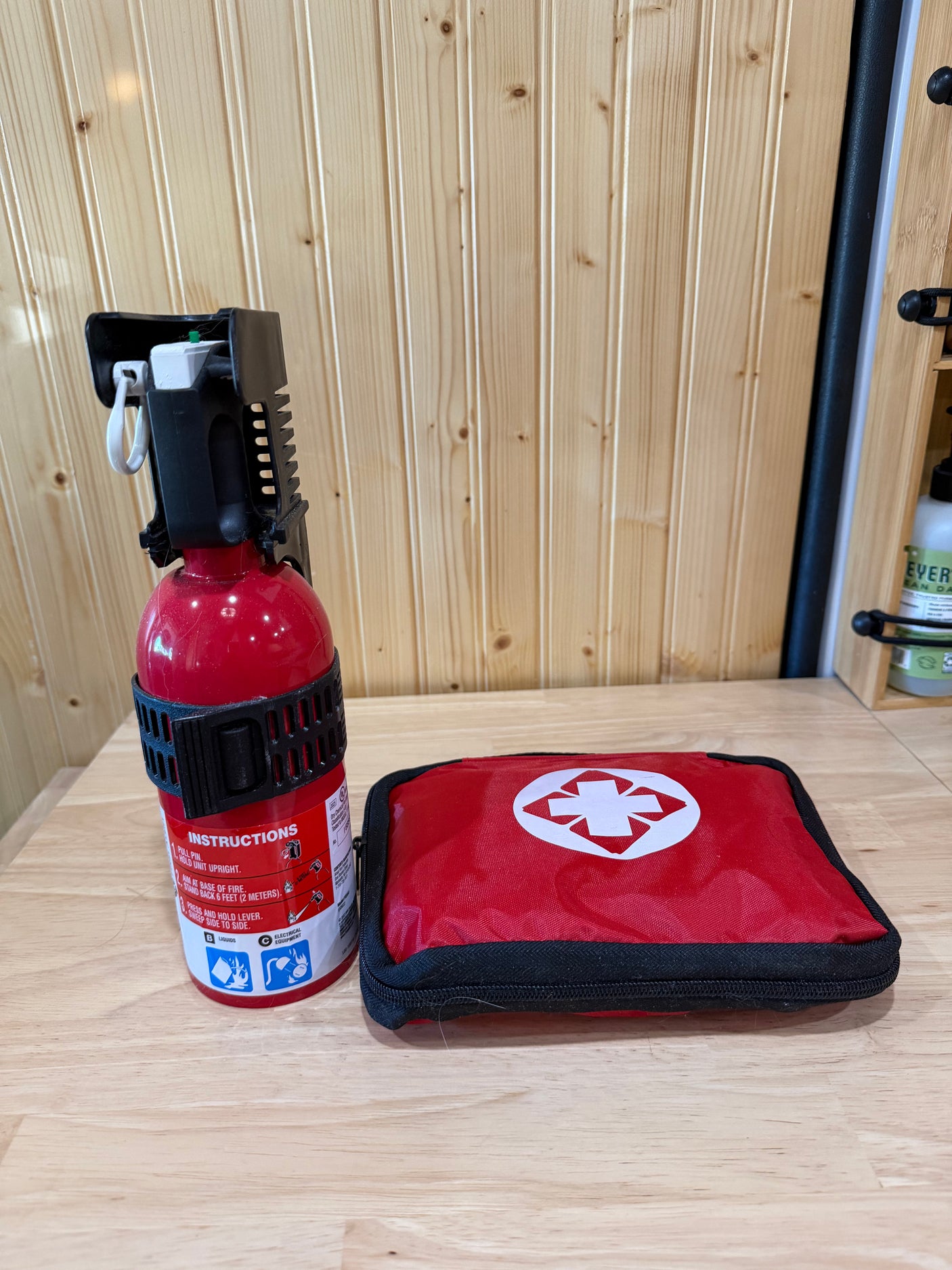 Essential RV rental safety gear: a fire extinguisher and a red first aid kit ready for emergencies on a wood surface.