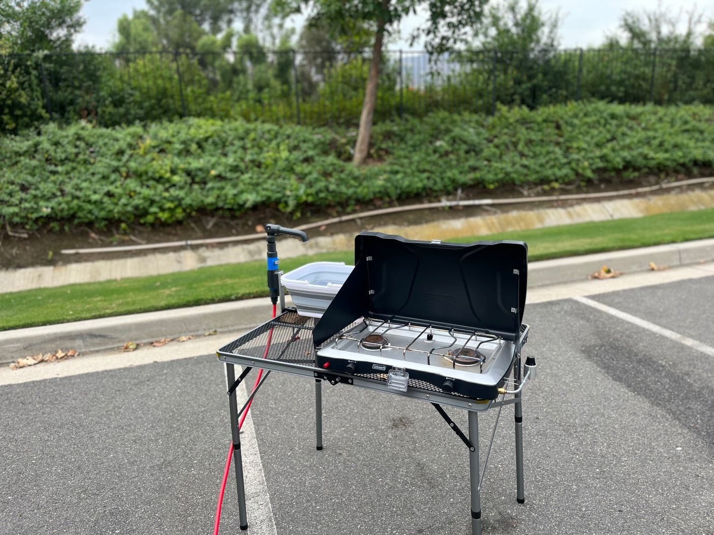 Portable outdoor kitchen setup with Coleman camp stove, sink, and table, perfect for your RV rental adventure.