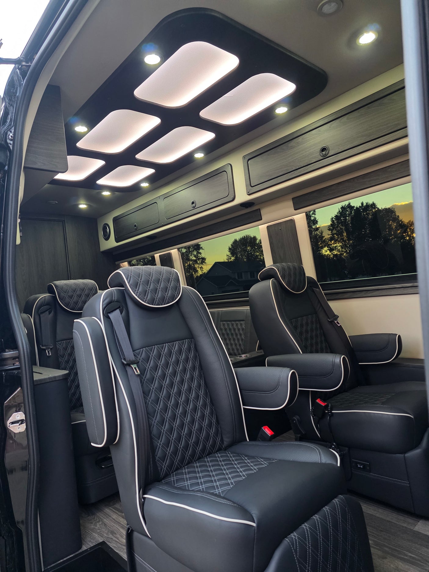 Luxurious RV rental interior: custom ceiling lighting, comfortable diamond-stitched seats, and elegant wood-look flooring.