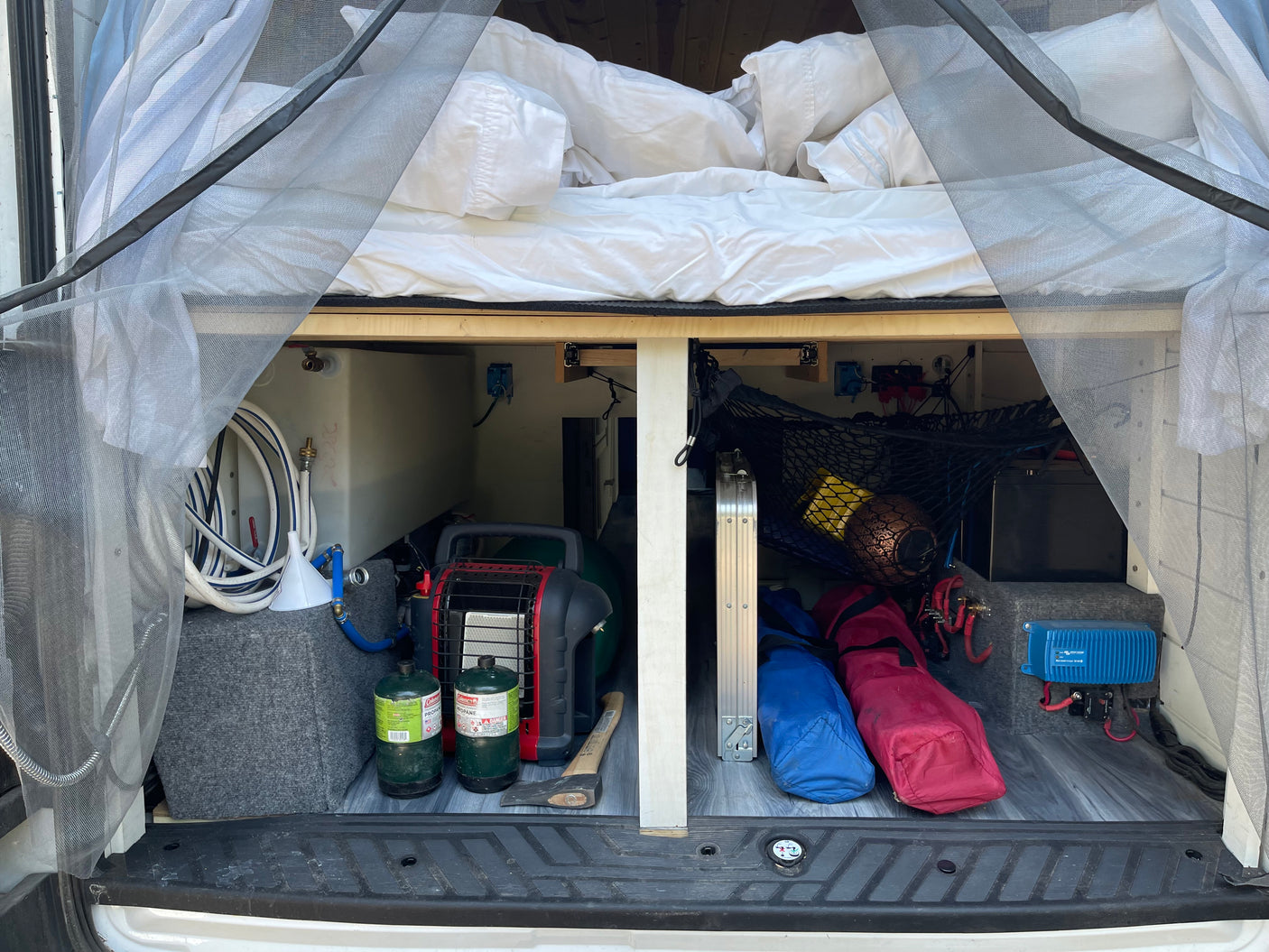 Explore this RV rental's clever under-bed storage: water tank, propane heater, and battery charger for camping comfort.