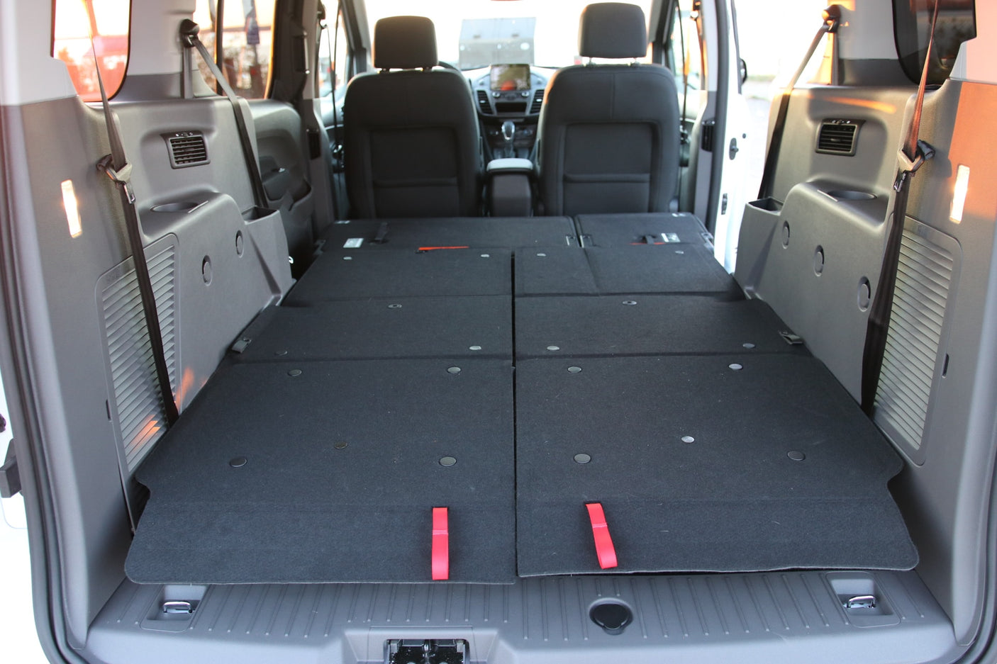RV rental interior with rear seats folded flat, revealing a versatile cargo or sleeping area in the van.