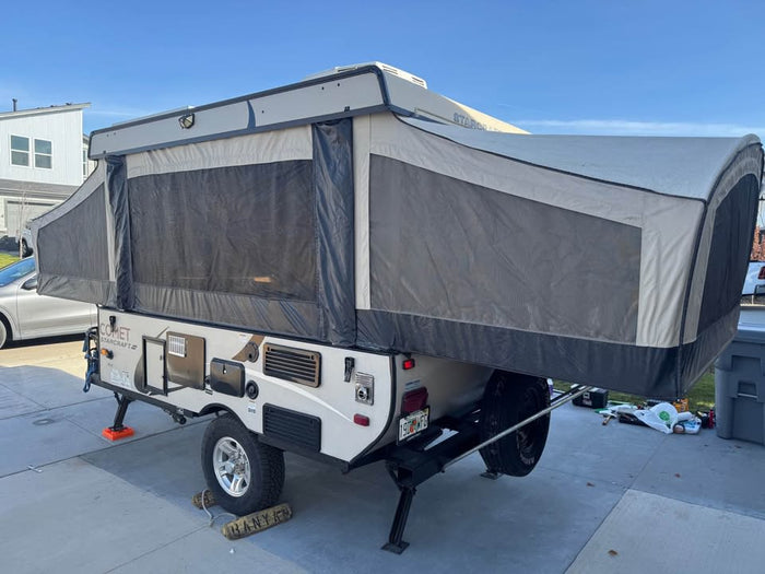 showing windows & steps.|Pop-up camper RV rental: A beige and dark grey Comet Starcraft model with extended tent sections