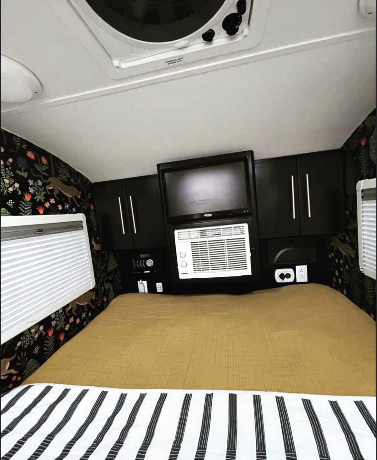 parked on a driveway.|Cozy rv rental bedroom with a striped bedspread