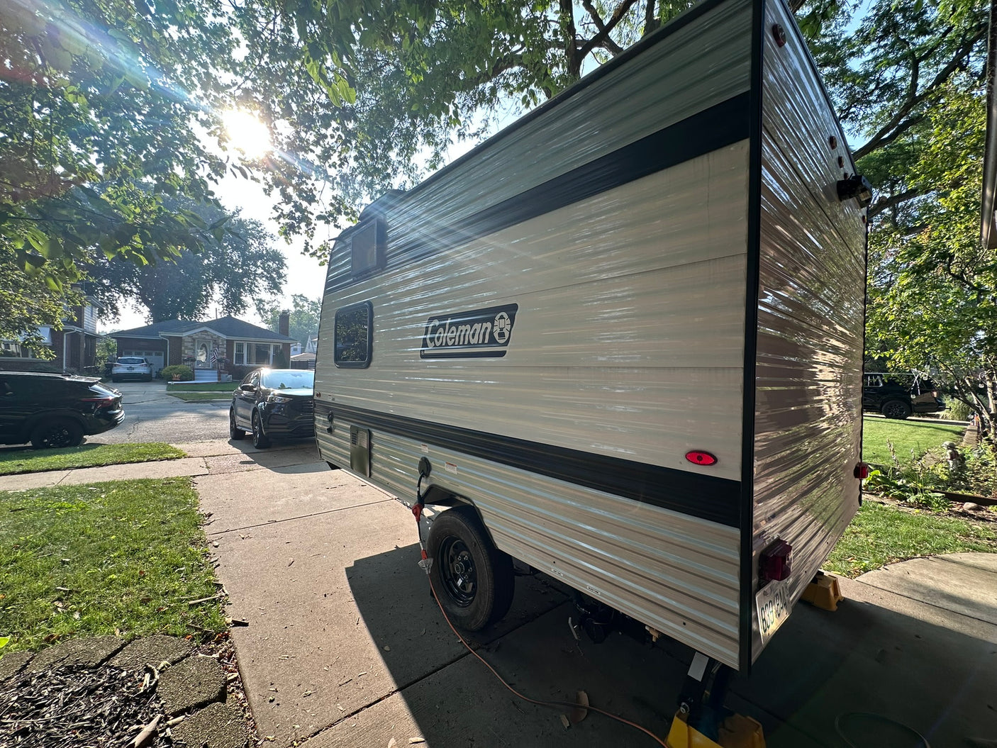 ready for your next RV rental adventure. Parked on a sunny driveway with trees overhead.|Rear view of a white RV