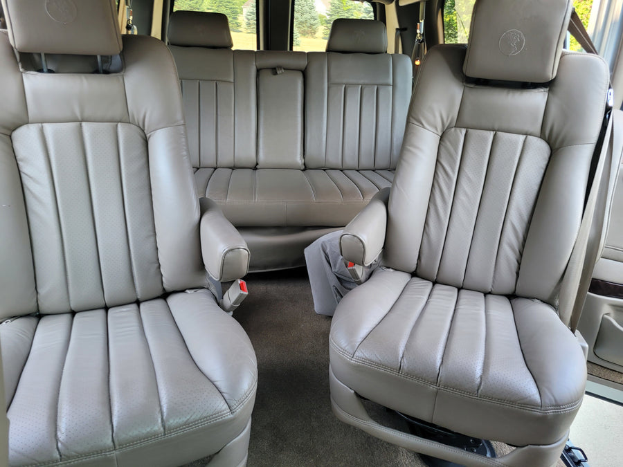 two captain's chairs & rear bench for comfort.|White van rv rental parked by a tranquil lake with forested mountains. Perfect for scenic road trips.|Comfortable Chevrolet RV interior