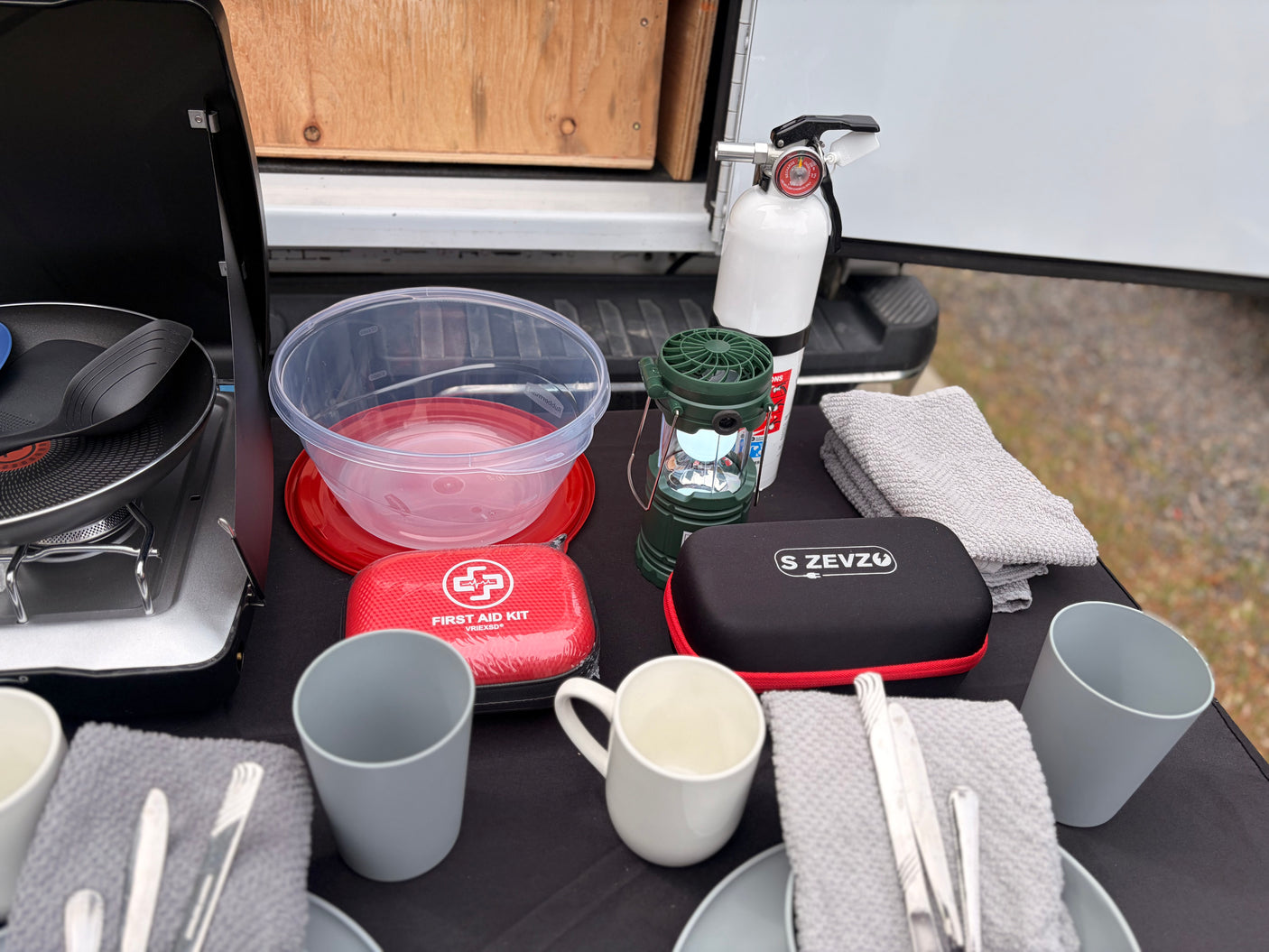 RV rental: Camping kitchen essentials for your adventure! Features stove, fire extinguisher, first aid, & dining gear.
