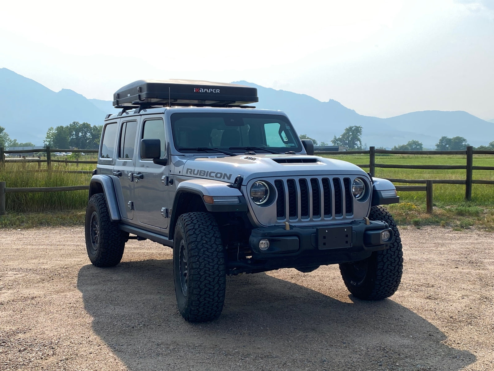 This silver Jeep Wrangler Rubicon with a roof-top tent offers an exciting RV rental alternative for off-road adventures.