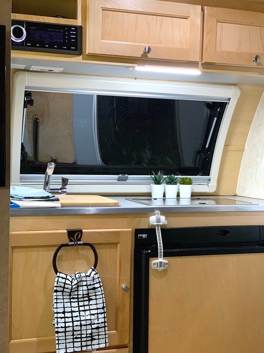 Functional RV rental interior: galley kitchen with sink, Norcold fridge, storage, and a multi-media stereo.