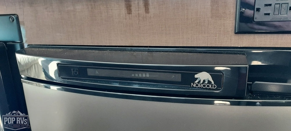 Close-up of a Norcold RV refrigerator's control panel, showing a digital display with power, 'A' mode, and temperature bars. Ideal for rv rental.