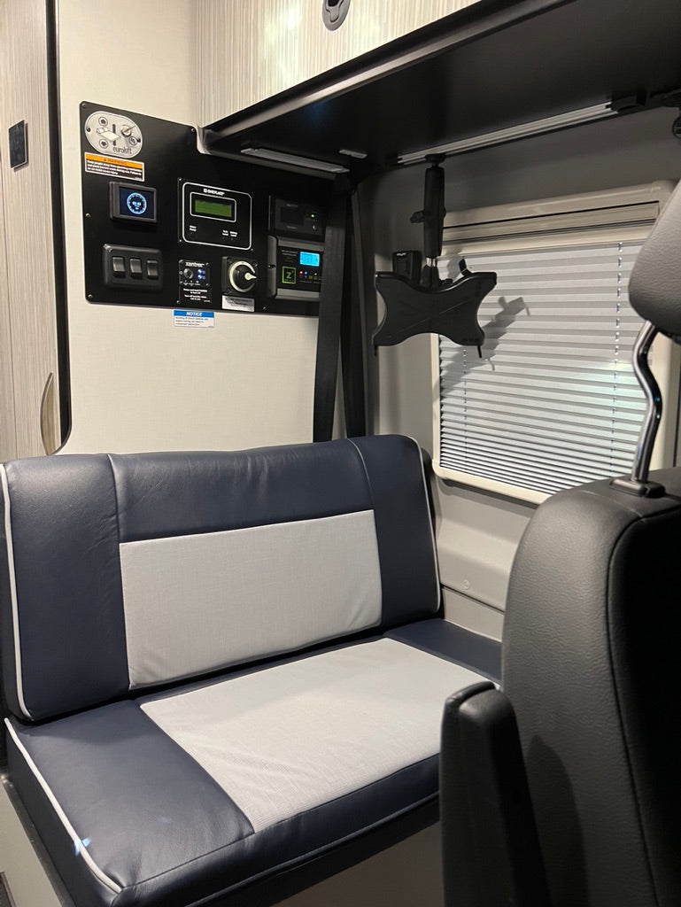 RV rental tech: main control panel, entertainment mount, and plush seating in a camper van interior.