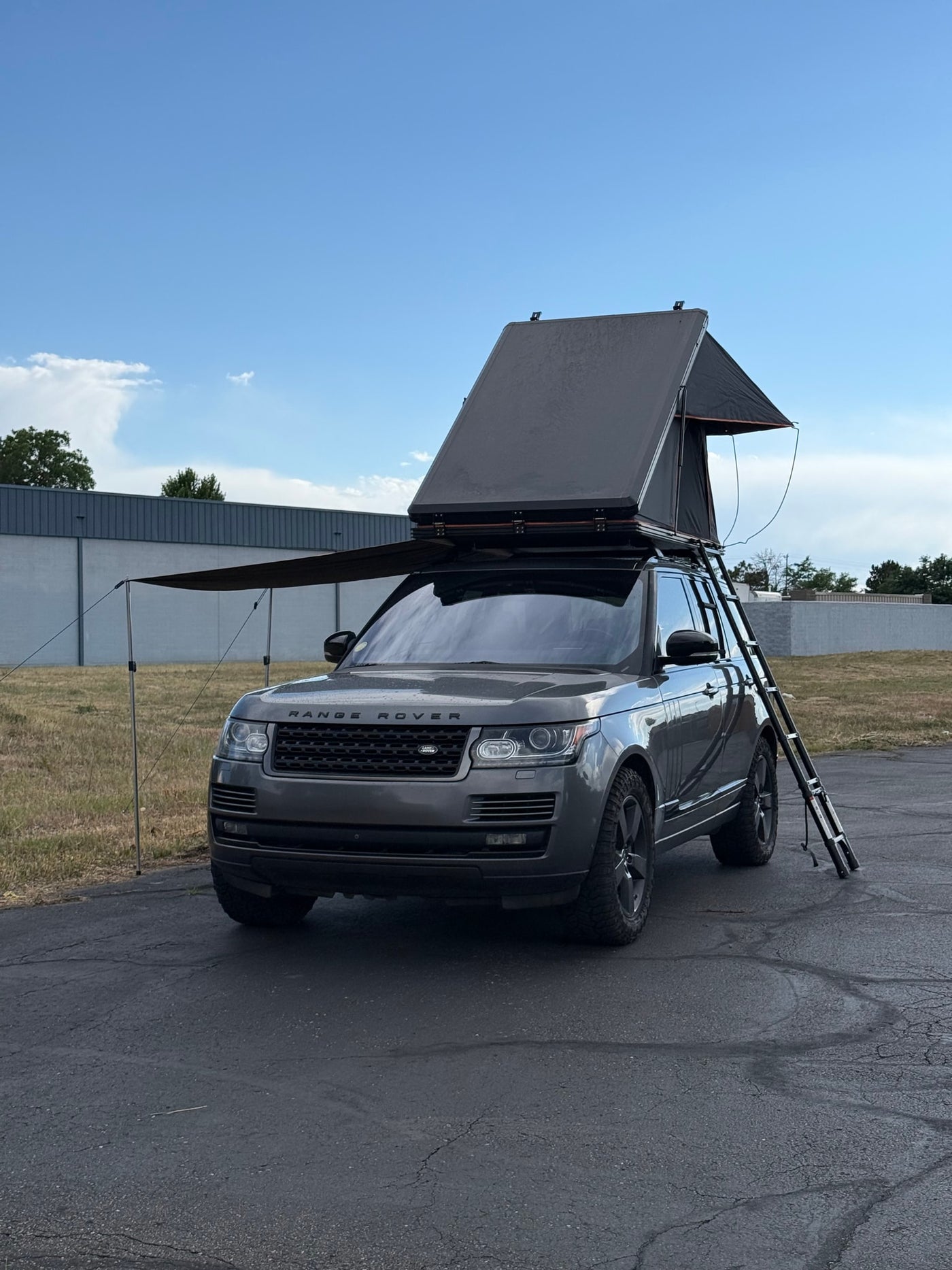 Dark grey Range Rover SUV with an open rooftop tent, ladder, and extended awning, perfect for an adventurous RV rental. — photo 8