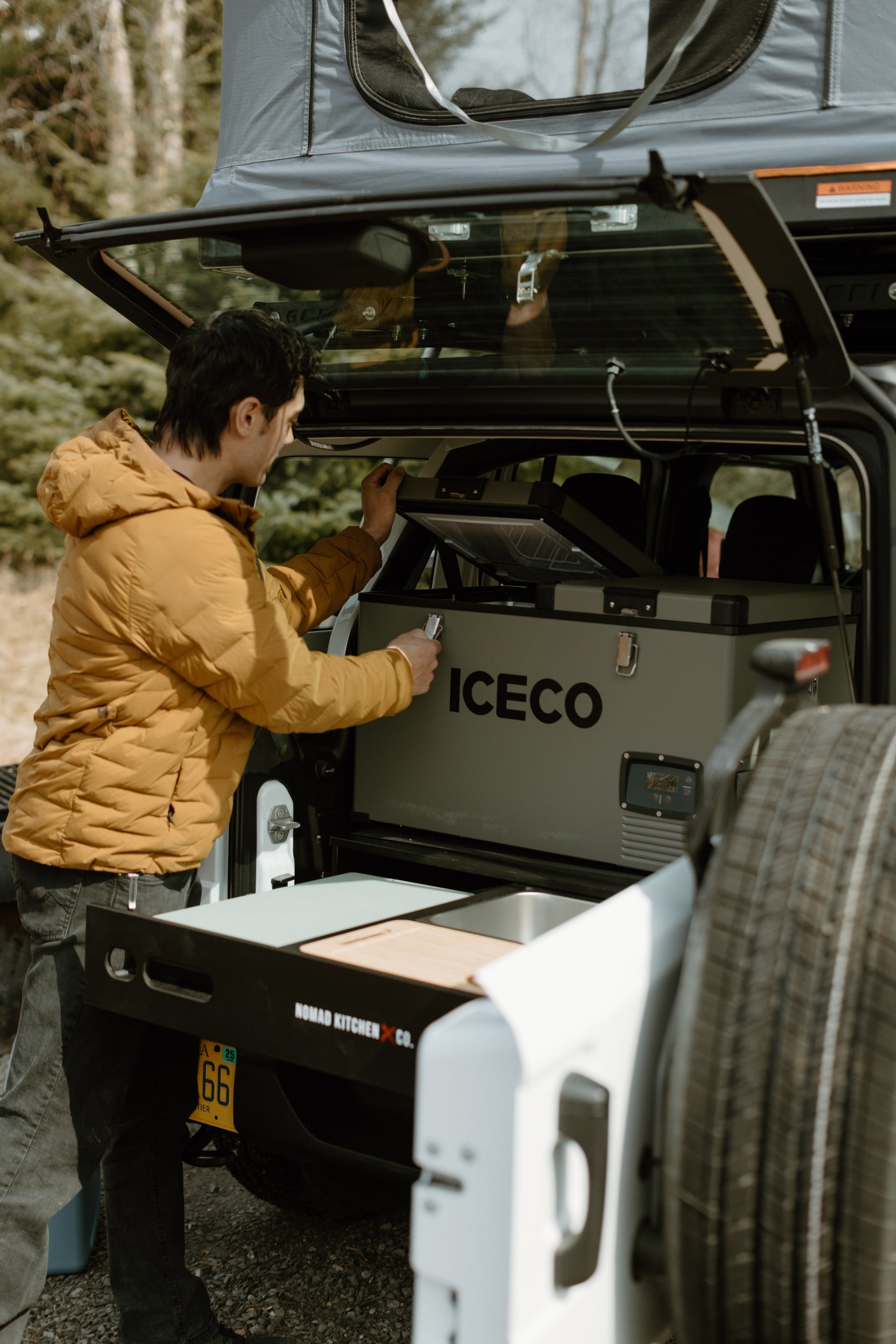 Man accessing ICECO cooler in vehicle's Nomad Kitchen setup, ideal for rv rental trips.