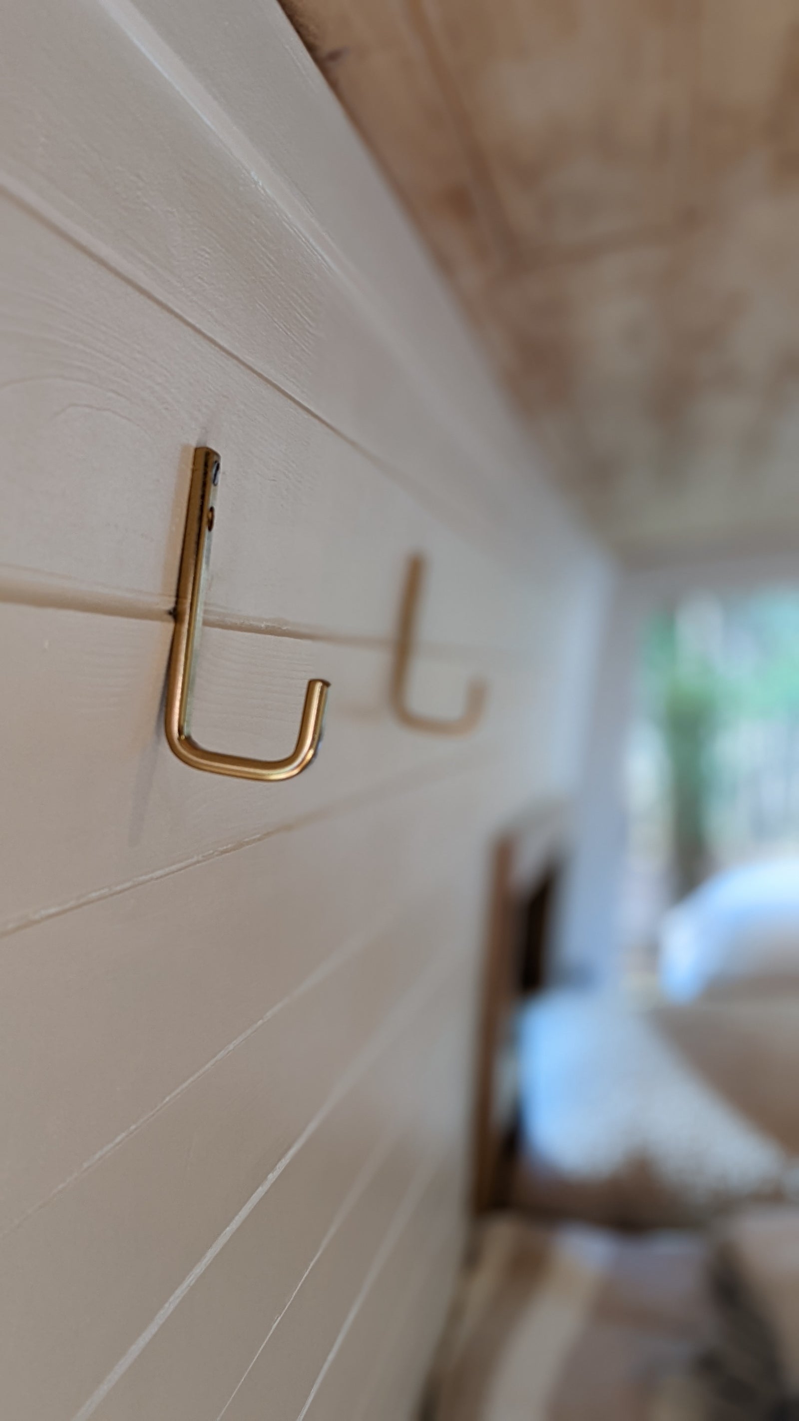 Stay organized on your RV rental journey! Close-up of gold hooks on the cozy, paneled interior wall of an RV.