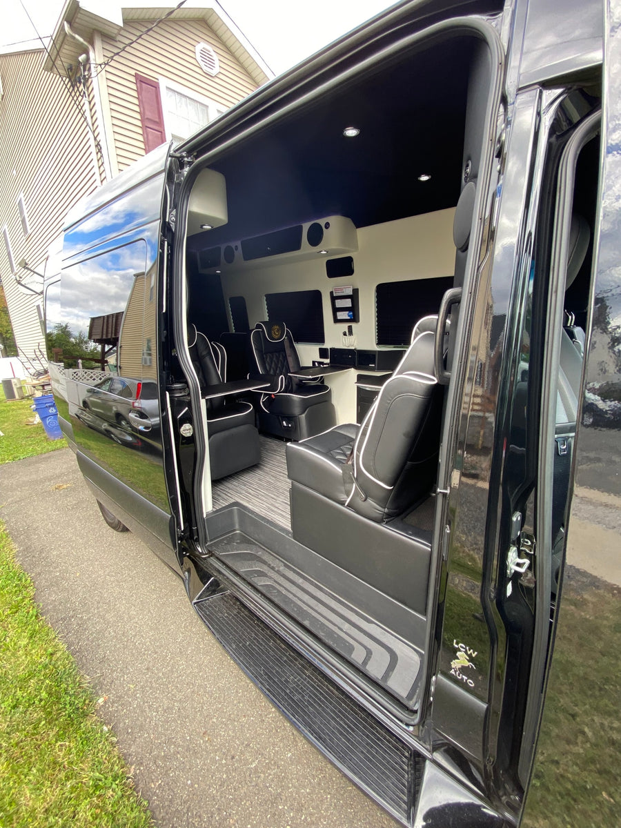 Luxury RV rental: spacious interior with black leather captain's chairs, fold-out tables, and ambient lighting. Ready for upscale travel.