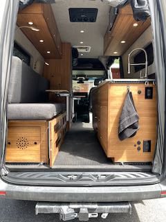 and front cab area.|Light-colored Sprinter camper van (RV rental) parked in golden light