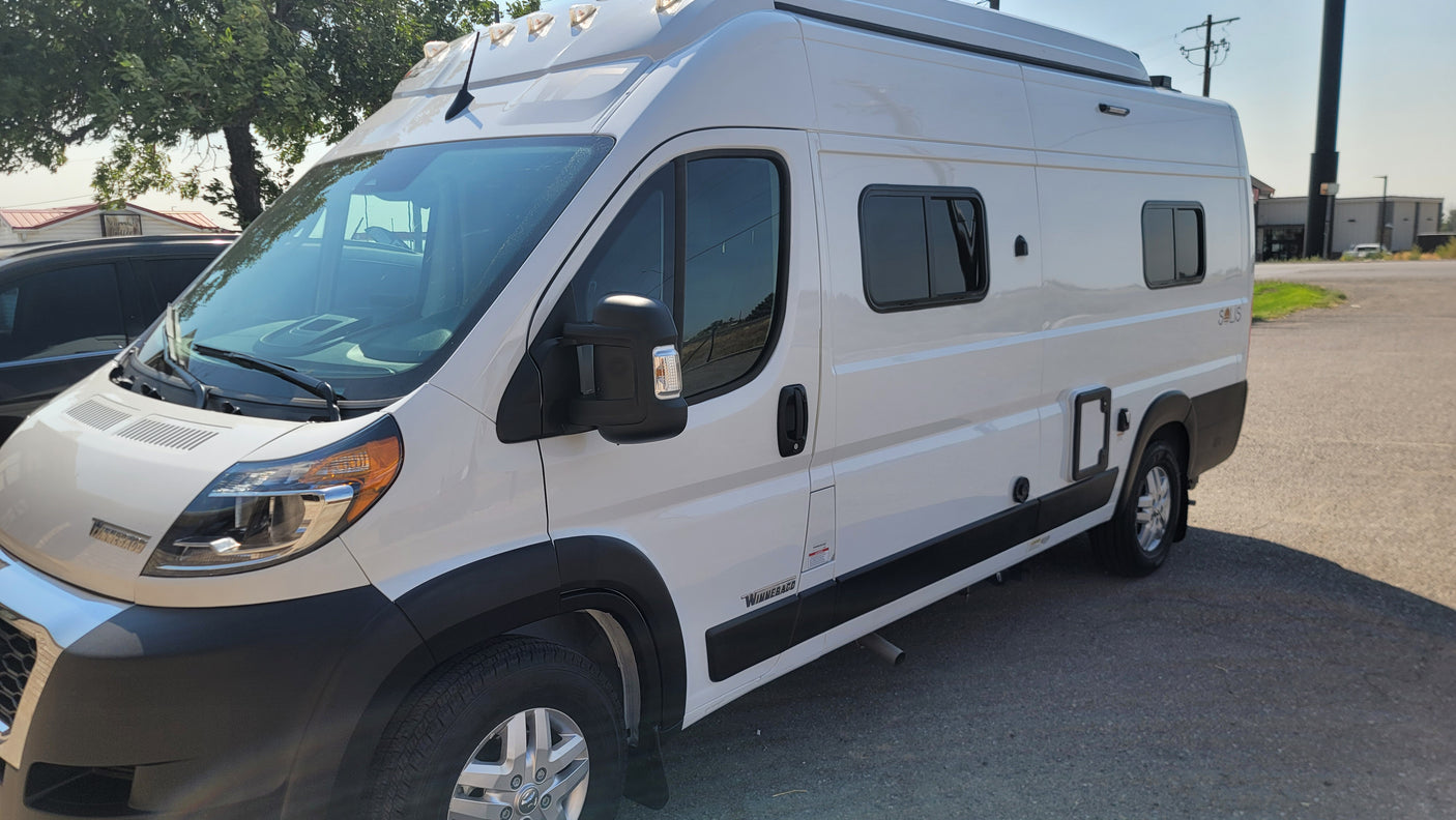 Side view of a white Winnebago camper van, ideal for an RV rental or a fun road trip.