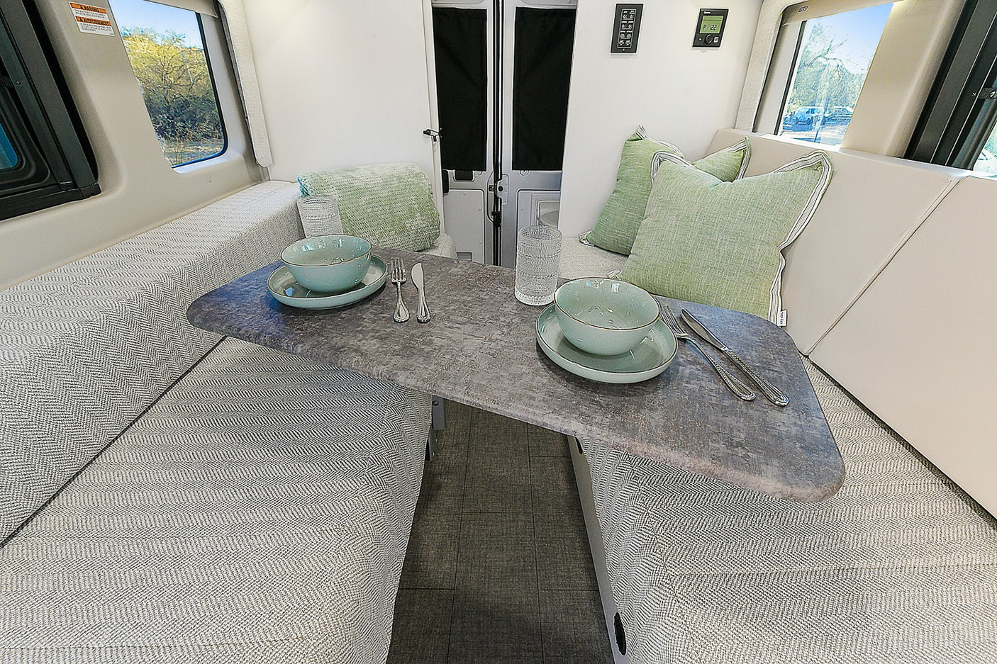 This RV rental offers a comfortable dinette setup with chevron patterned cushions and a stone-look table, ready for dining.