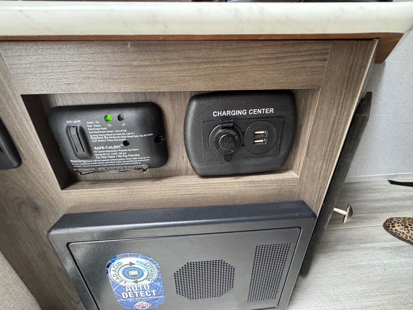 sits on the floor with a mesh storage net attached below it.|An RV rental interior showing a mounted fire extinguisher