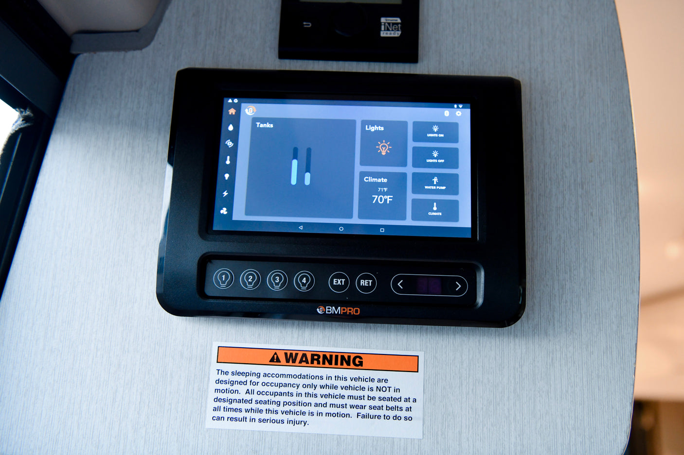 RV rental's BMPRO smart control panel shows tank levels, lighting, climate, and a critical safety warning sticker.