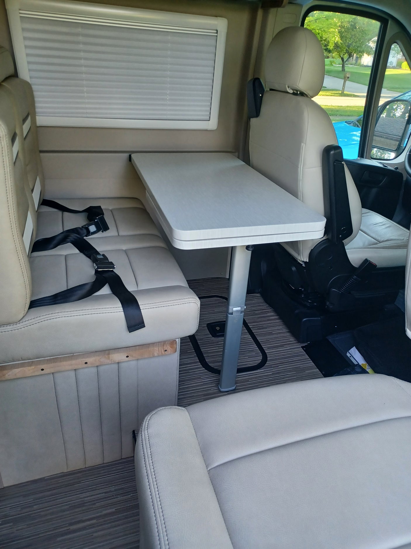 RV rental interior with swiveling front seats, a retractable table, and beige rear seating with seatbelts for comfortable travel.