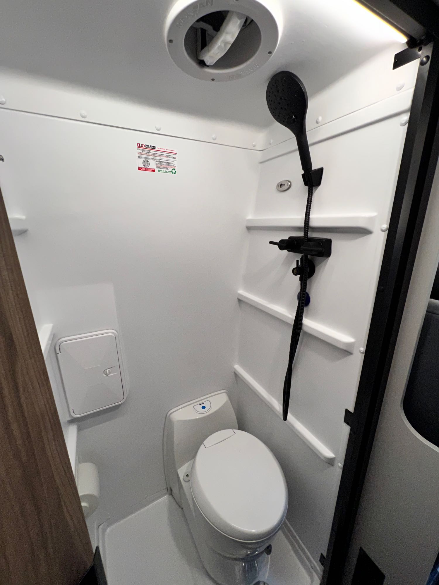 Experience comfort in a compact RV rental wet bath, complete with a toilet, shower, and ceiling vent for travel.