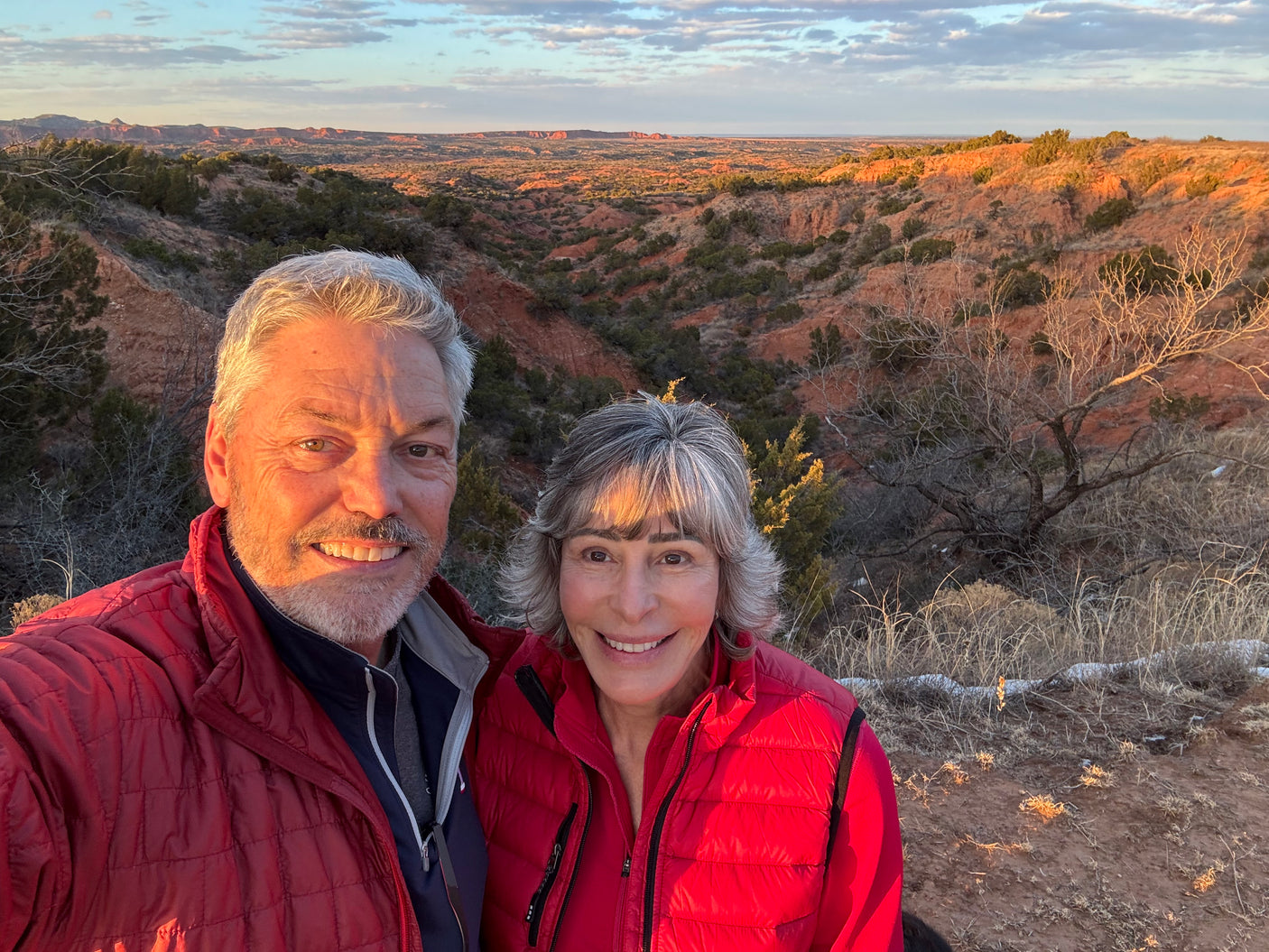 Couple beams, showcasing a breathtaking canyon sunset, a memorable stop on their RV rental journey. Red rocks and golden light fill the scene.