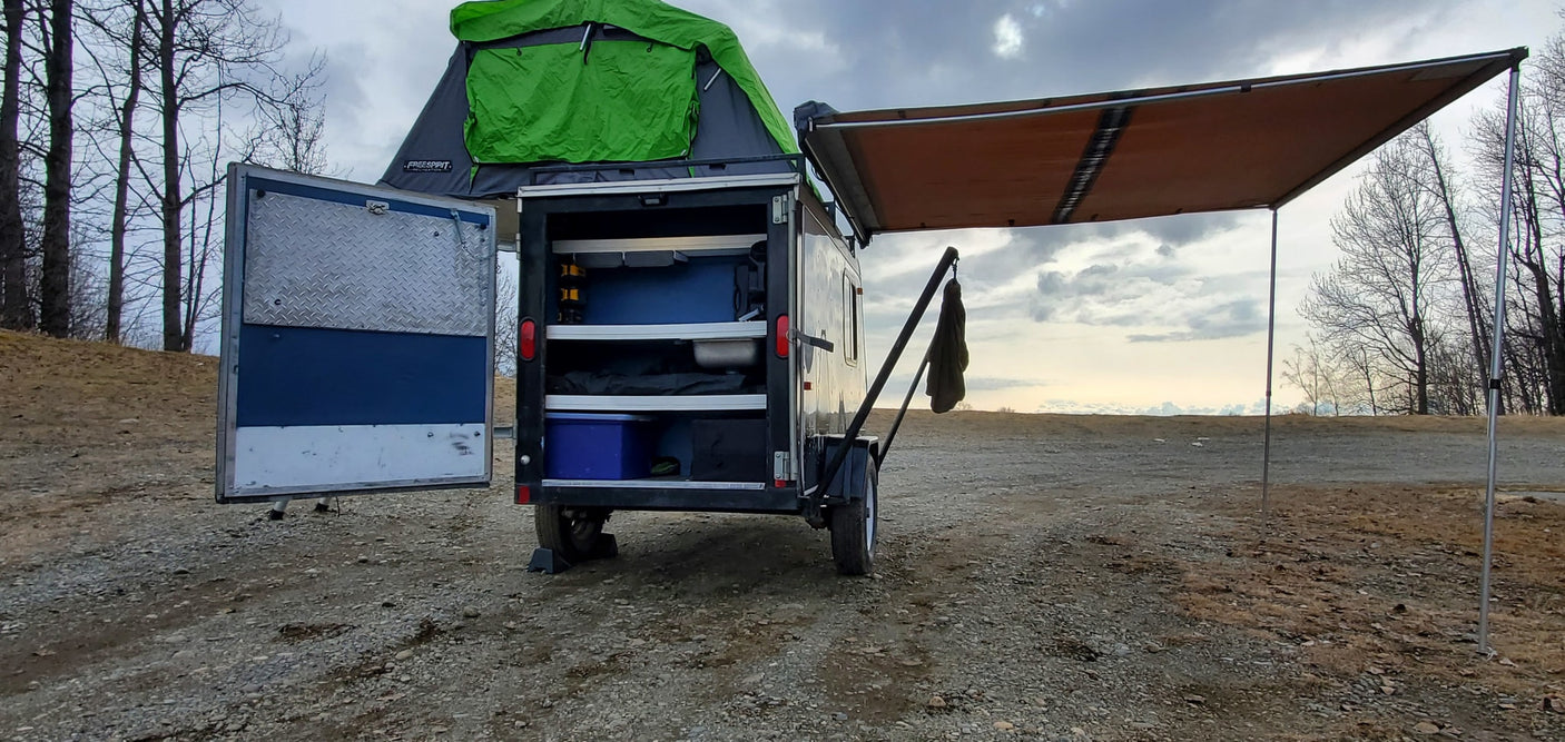 Compact rv rental trailer with a rooftop tent, organized storage, and side awning for versatile outdoor trips.