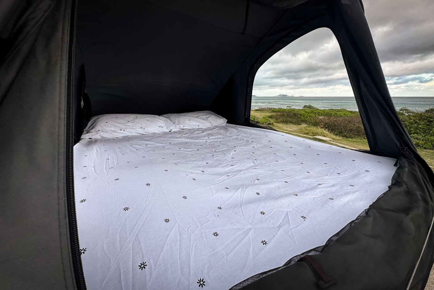 RV rental: Cozy bed in a pop-up tent with a stunning ocean view. Ideal camping setup!