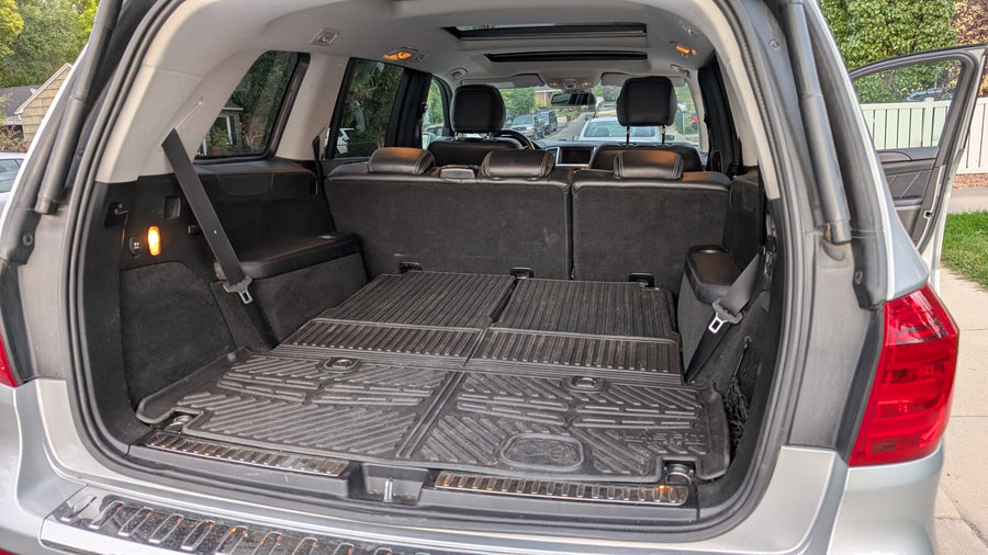 Spacious SUV trunk interior with folded seats, rubber mats, & power outlet, ideal for any rv rental or travel gear.