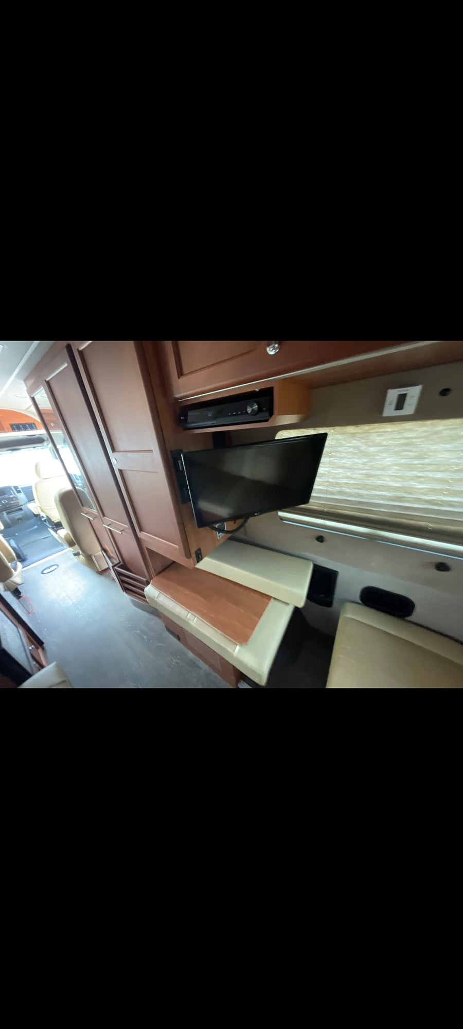 Inside this RV rental: a well-appointed living space with a cozy dinette, wall-mounted TV, and entertainment console.