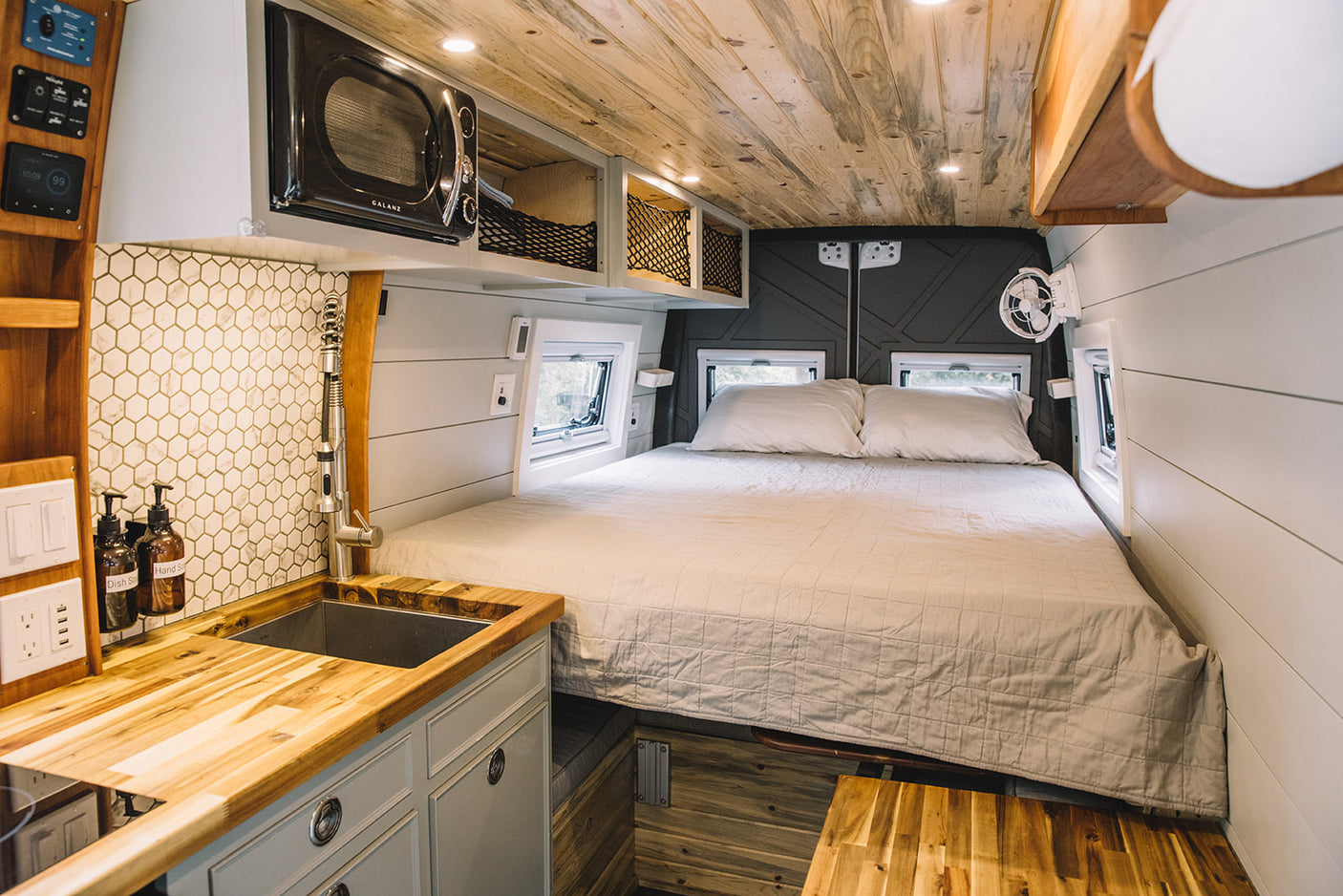 Cozy RV rental interior featuring a built-in bed, fully equipped kitchenette, and warm wood accents.