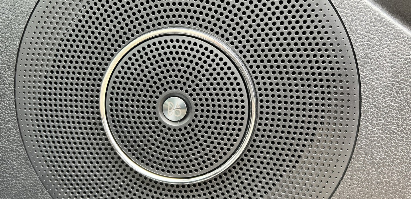 RV rental: High-fidelity B&O audio speaker grille, showing perforated pattern and chrome ring.