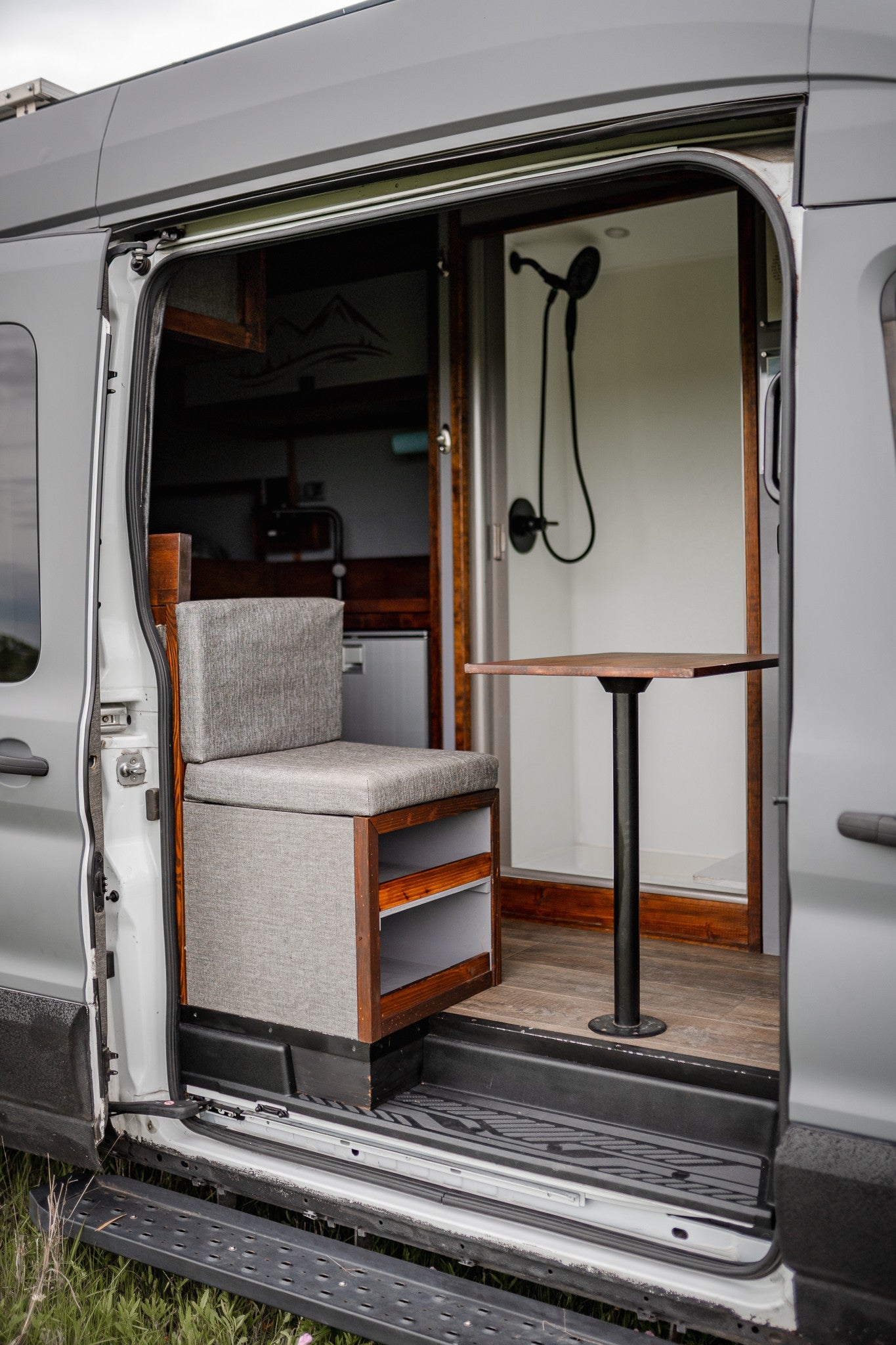 RV rental van interior: cozy seat, dining table, and compact shower for mobile living.