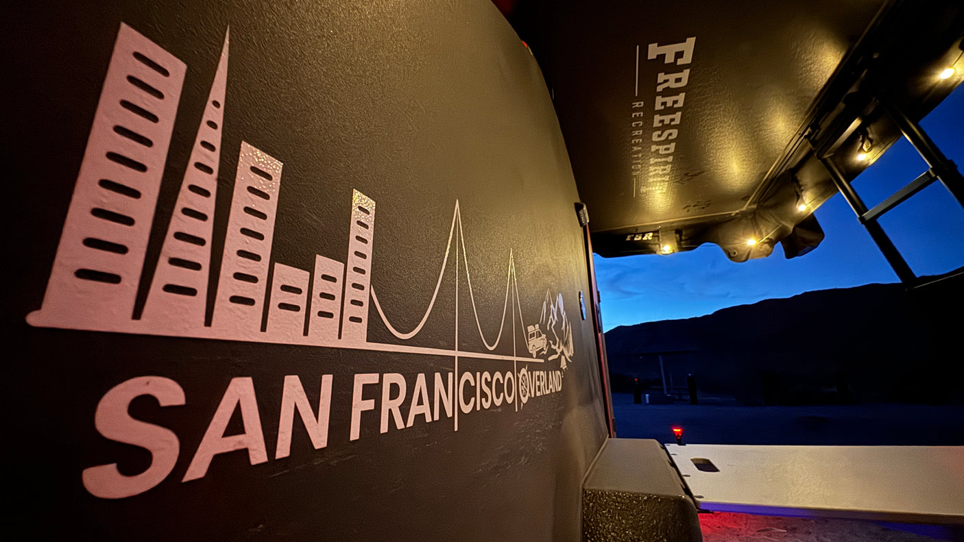 San Francisco Overland RV rental shows cityscape graphic & Freespirit Recreation tent setup at dusk, ready for adventure.