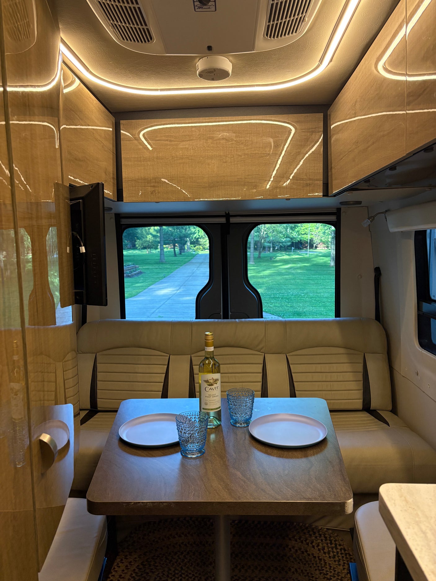 Cozy RV rental dining area: set for two with wine & a view. Perfect for travel and relaxation in your camper van!