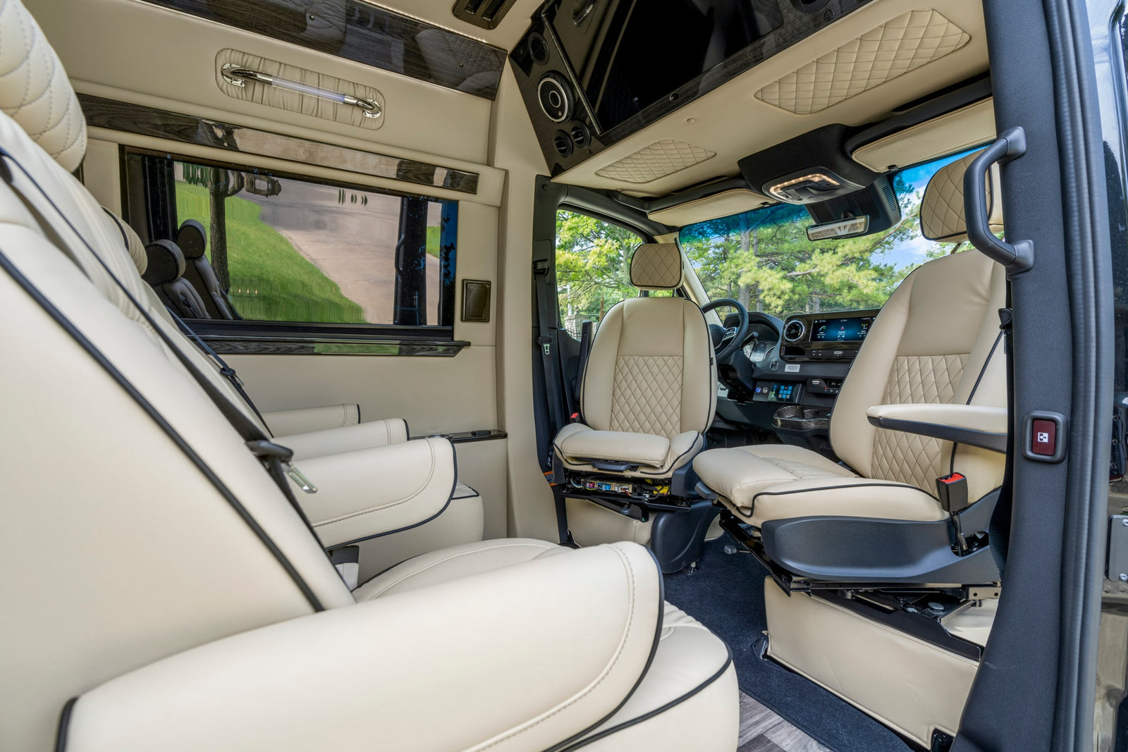 Inside a spacious RV rental: luxurious cream interior with quilted seats, dark wood accents, and modern amenities for travel comfort.