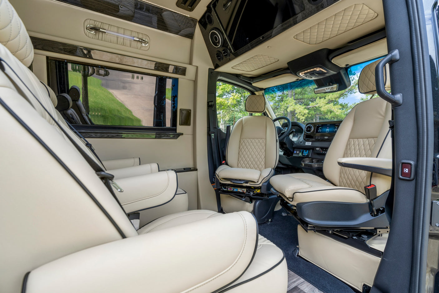 Inside a spacious RV rental: luxurious cream interior with quilted seats, dark wood accents, and modern amenities for travel comfort.