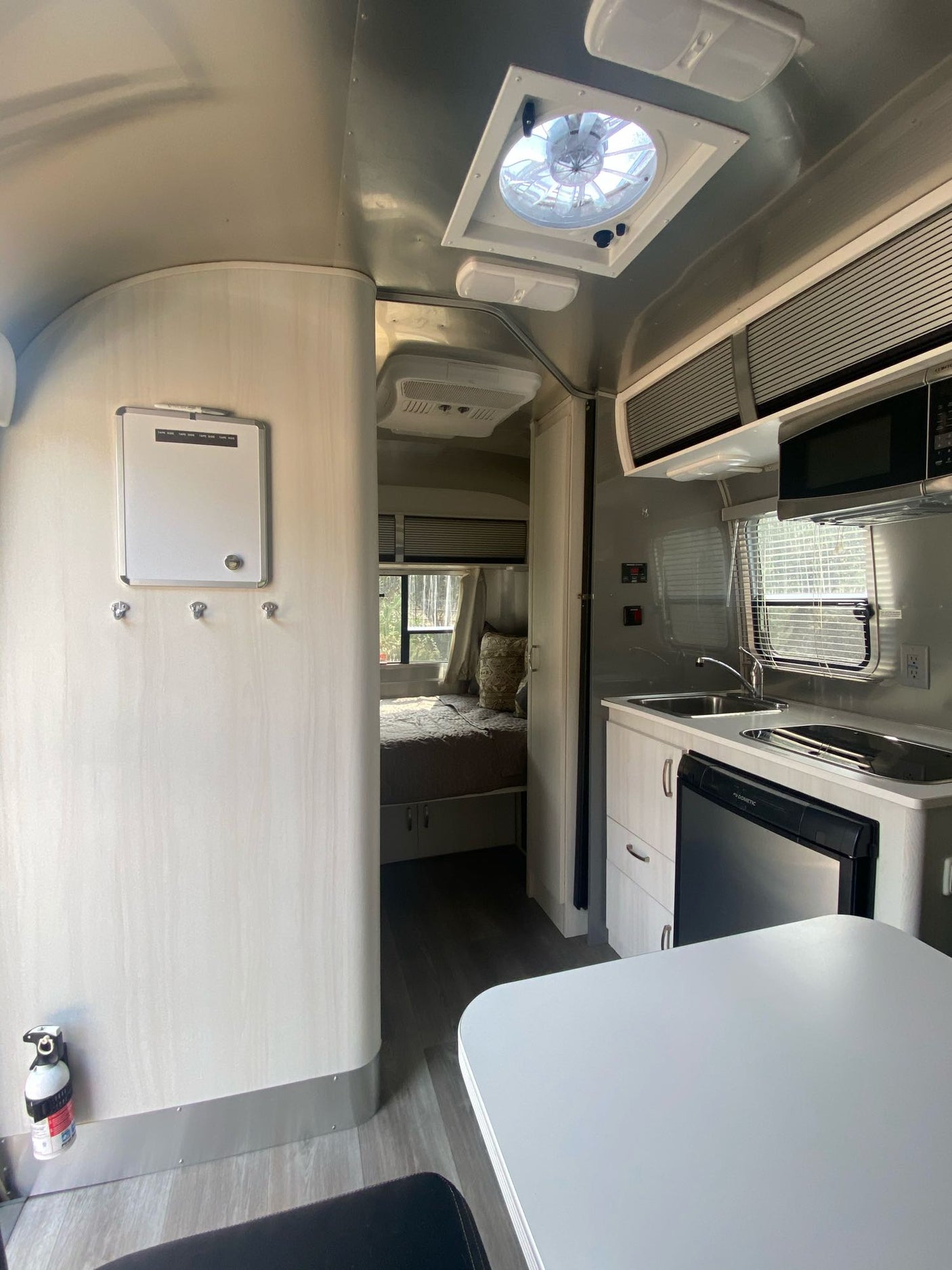 Step inside this modern RV rental, featuring a compact kitchen, dining area, and cozy bedroom ready for your travels.
