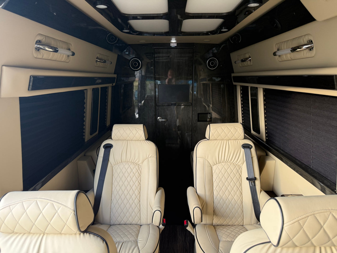 Plush RV rental interior features cream quilted leather captain's chairs, dark wood paneling, TV, and chrome accents for comfort. — photo 4