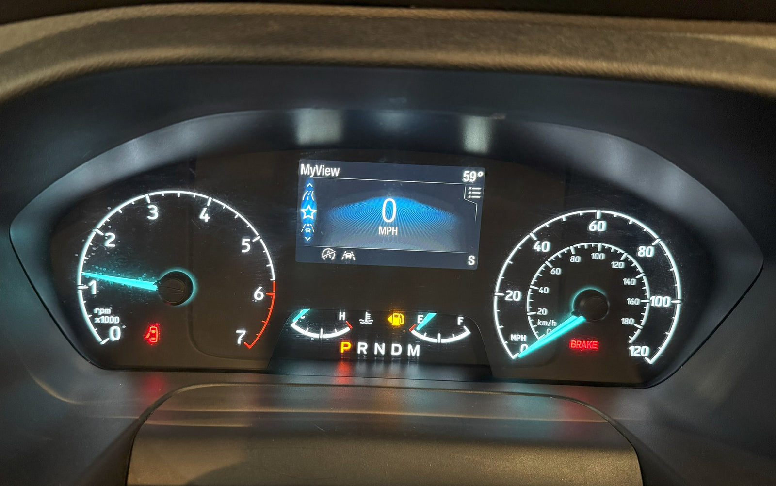 This RV rental's dashboard displays 0 mph, 59° ambient temperature, low fuel, and illuminated brake/door warning indicators.