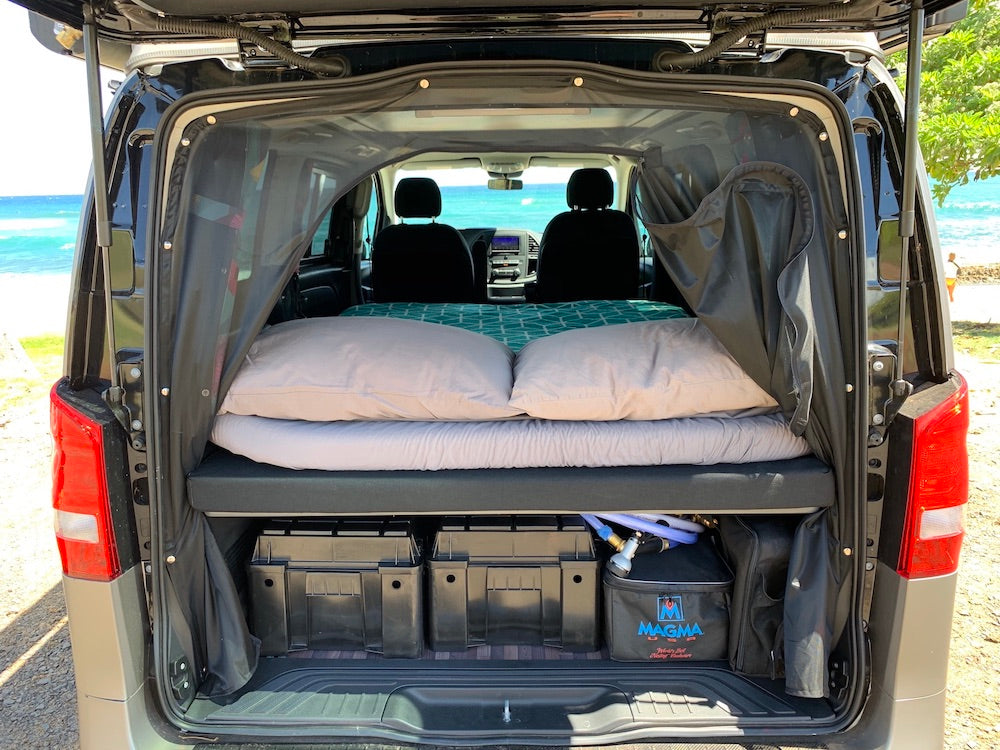 This RV rental campervan features a cozy bed, ample storage, and ocean views for your next camping road trip.