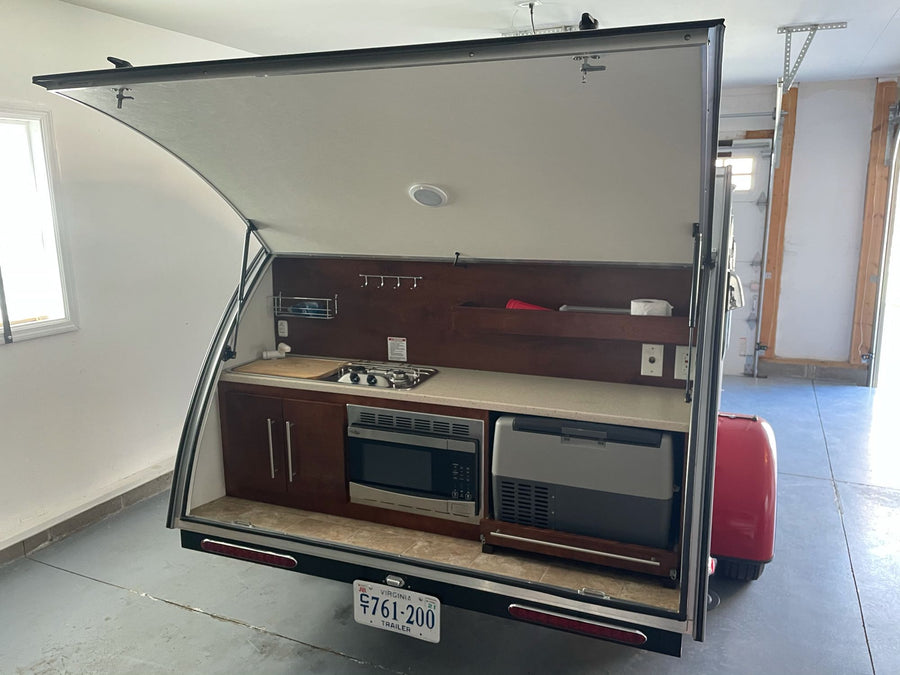 and wood cabinets.|Compact & cozy RV rental interior: spacious bed