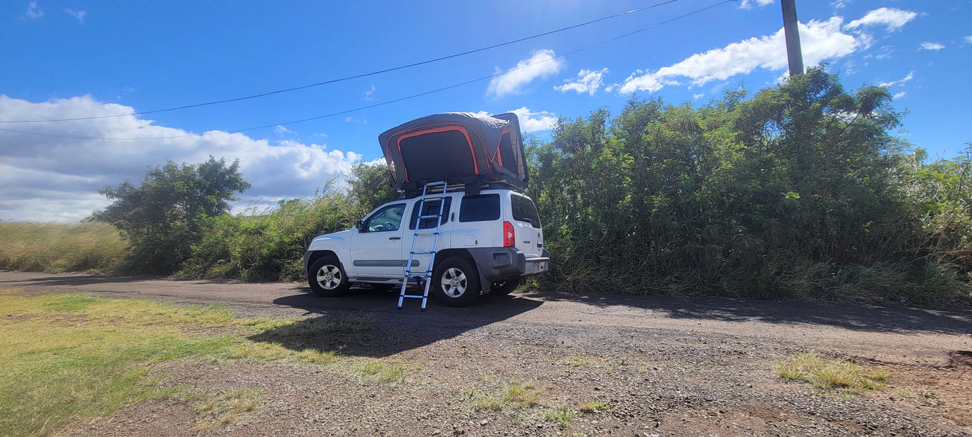 White SUV with an open rooftop tent & ladder. A great compact RV rental option for nature adventures.