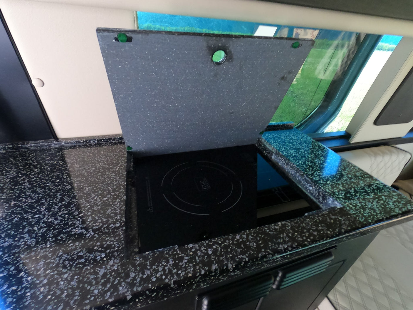 RV rental kitchen: compact induction cooktop with a hinged cover in a sleek speckled countertop.