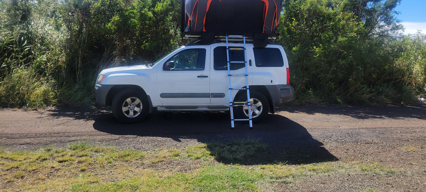 White Nissan Xterra with rooftop tent & ladder for your next **RV rental** adventure. Perfect for overland camping on dirt roads.