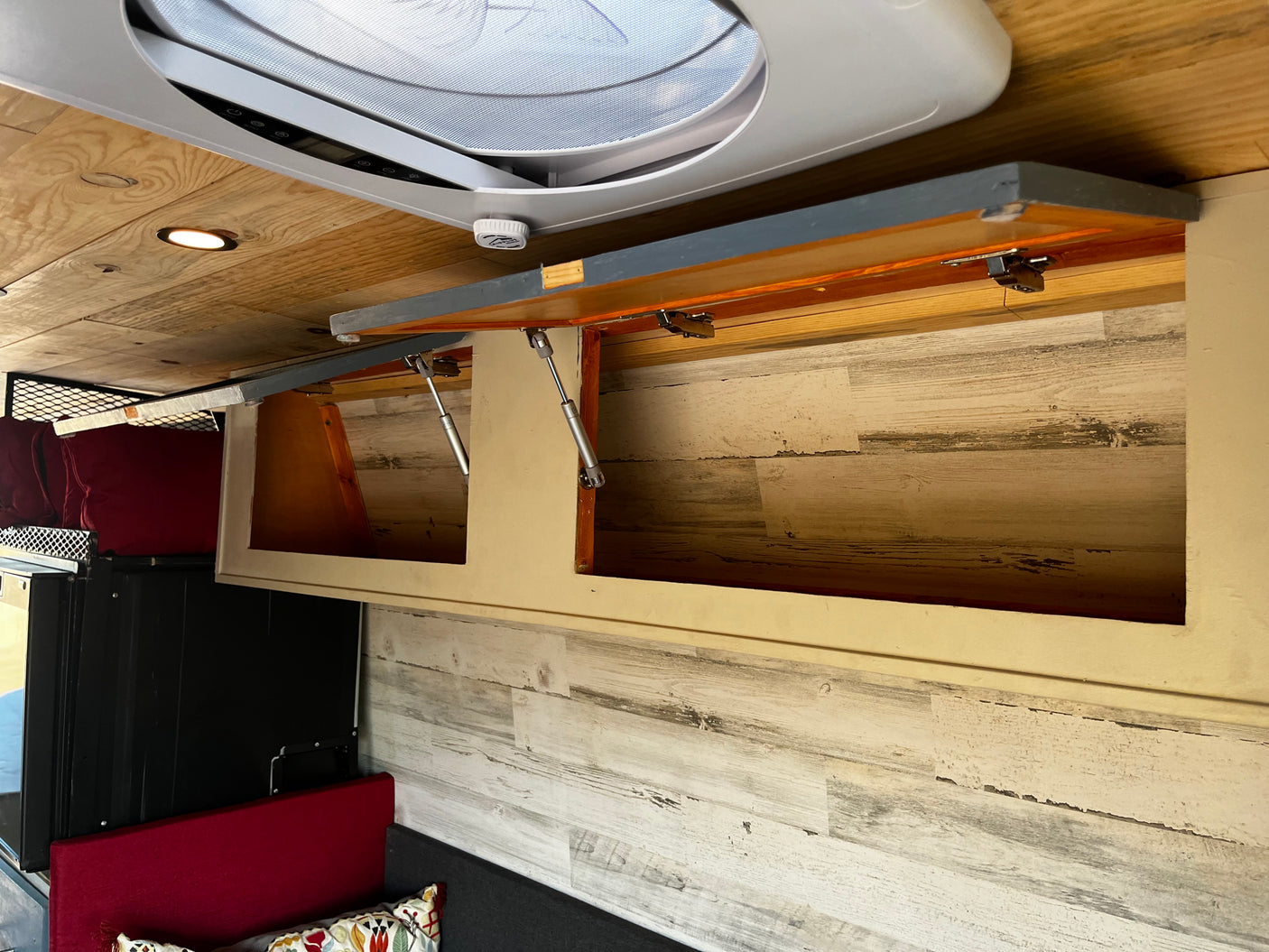 RV rental custom interior: open overhead storage cabinets with gas struts, a ceiling fan, and recessed lighting on a wooden ceiling.