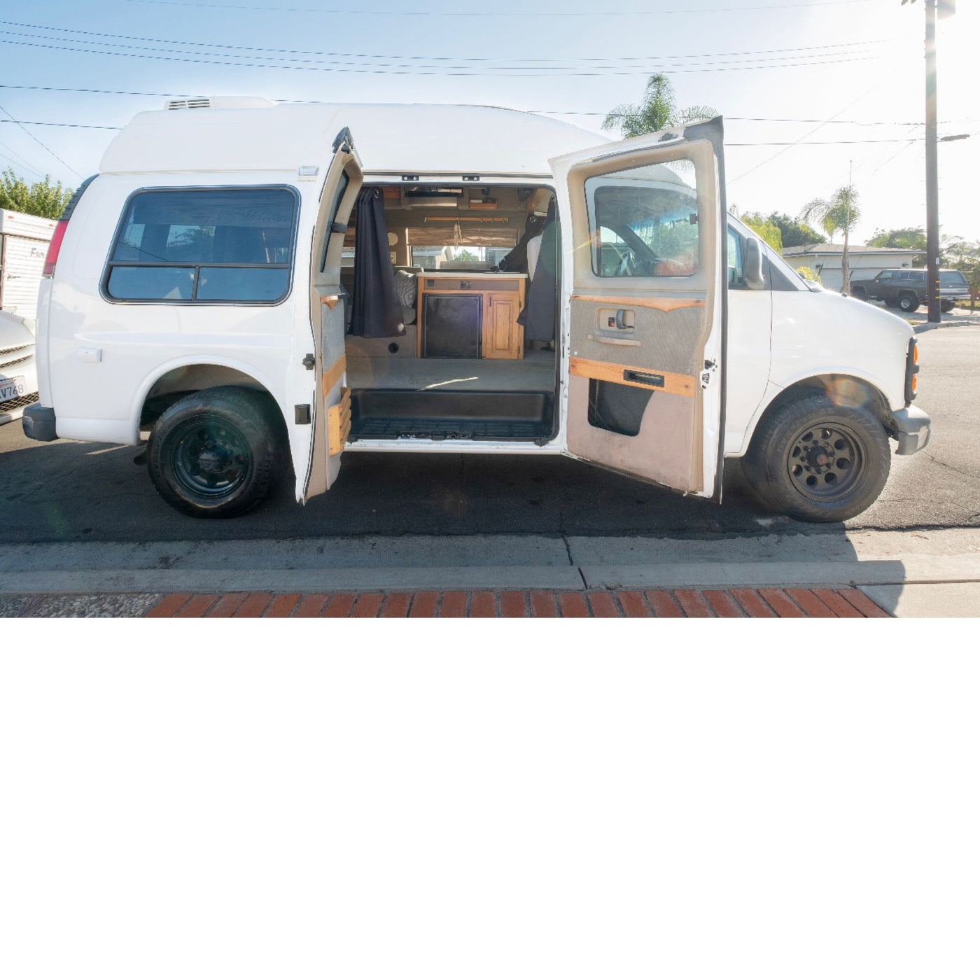 and driver's cabin visible through the front.|White high-top GMC van — photo 9