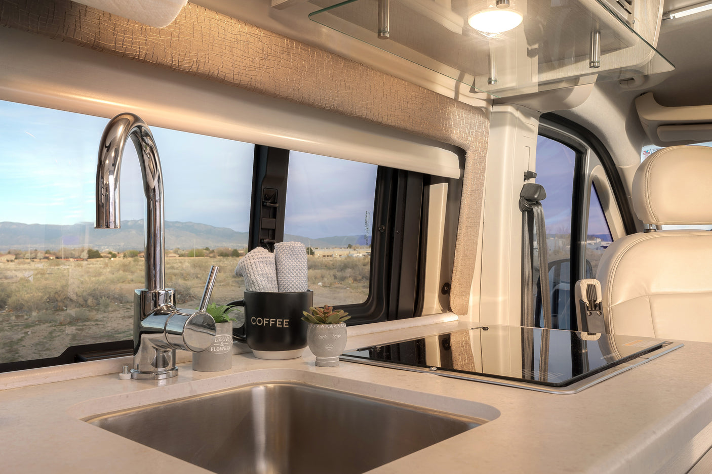 RV rental kitchen featuring a compact sink, induction cooktop, and scenic window view for comfortable mobile living.