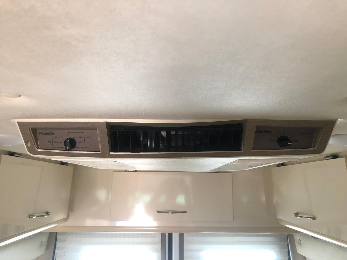 RV rental interior showing ceiling AC unit with Penguin and Duo-Therm controls, plus white overhead storage cabinets.